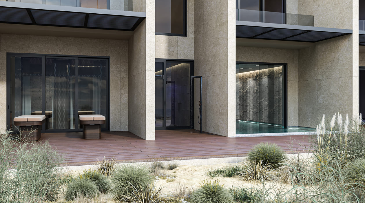 The exterior of a modern home spa with a spacious terrace, featuring two chairs, large windows, and surrounded by natural, drought-tolerant landscaping.
