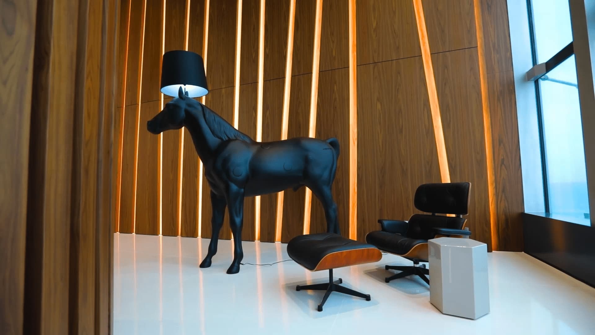 The image features a modern interior with a quirky horse-shaped lampstand and a classic mid-century modern chair set against a backdrop of vertical wooden slats and warm lighting.