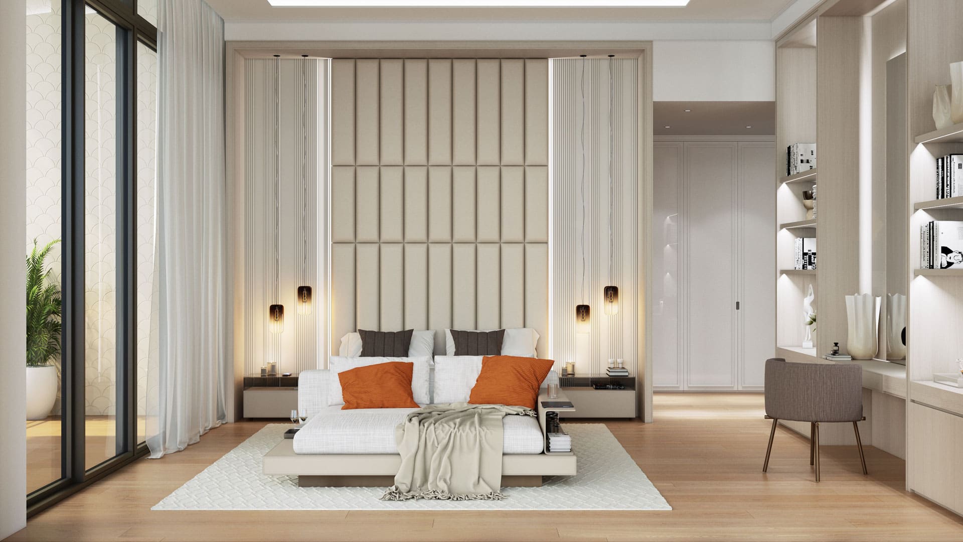 A spacious bedroom with a large bed centered against an upholstered wall panel, with a plush throw and orange accents, flanked by lamps and nightstands, adjacent to a bright window area and a sleek study corner with shelving.